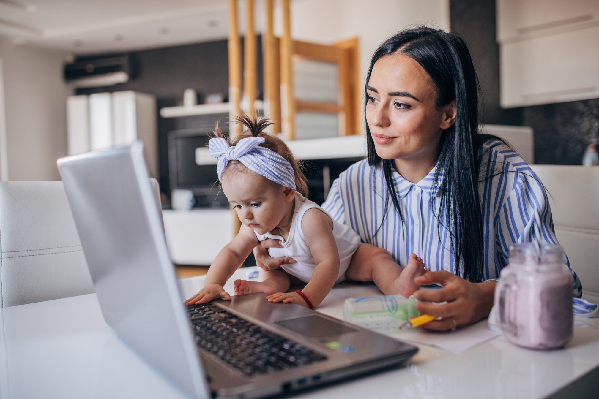 Modern mom holding a baby and using laptop